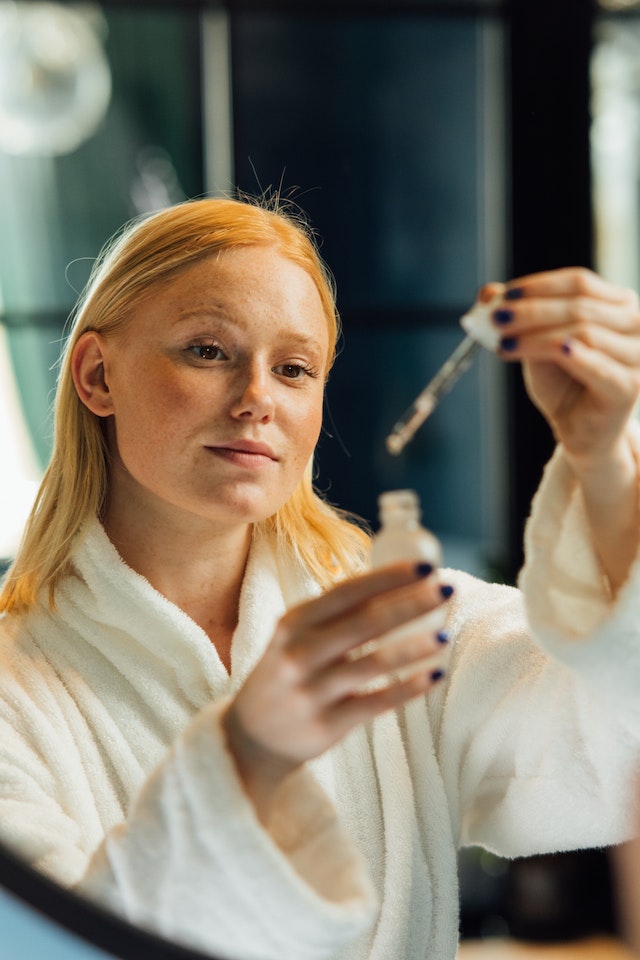 Woman looking in mirror about to apply facial serum