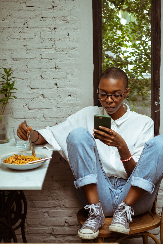 woman texting while eating pasta