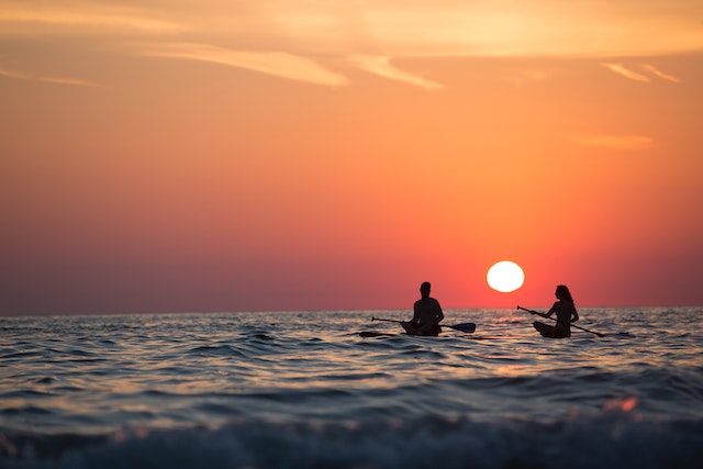 couple paddleboarding at sunset