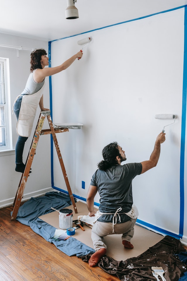 couple painting a wall white