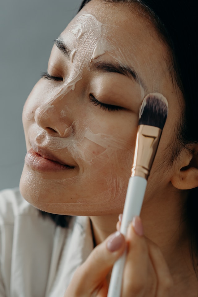 woman applying face mask with brush