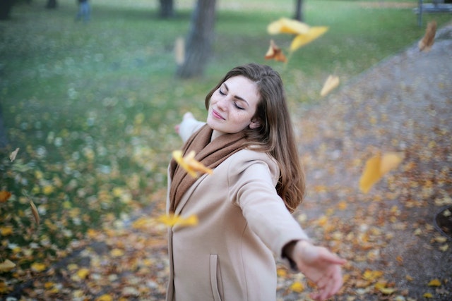 woman twirling and throwing leaves