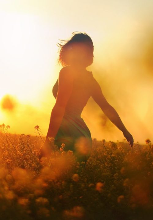 Silhouette of a woman in a field at sunset, enjoying the warm golden light. A visual representation of romanticizing life by savoring simple moments and embracing nature.