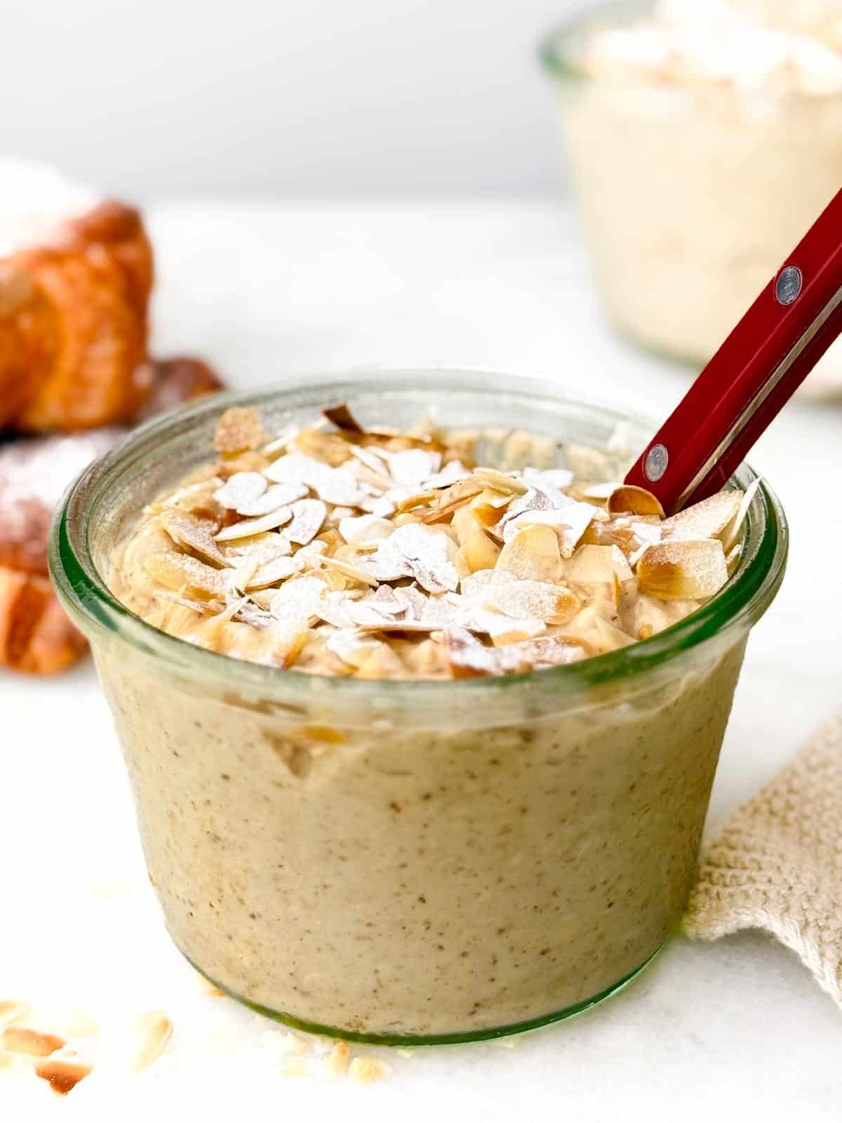 Almond croissant overnight oats in a jar topped with sliced almonds