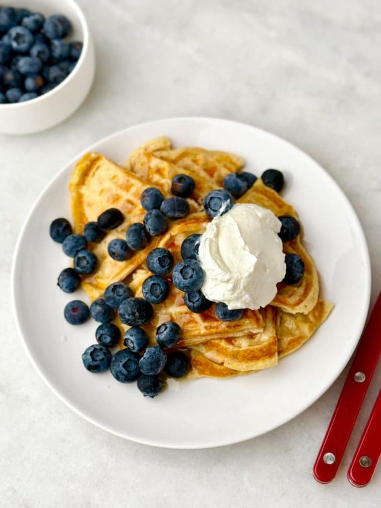 Protein waffles on a plate with blueberries and whipped cream