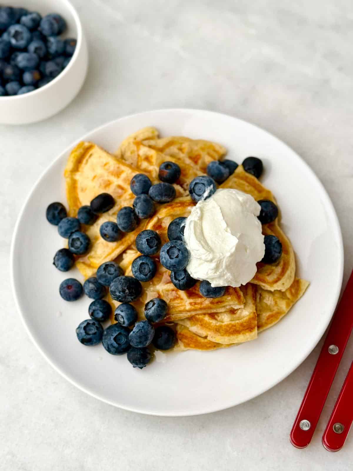 Protein waffles on a plate with blueberries and whipped cream