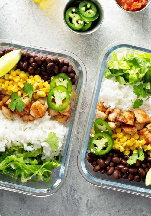 Healthy lunch meal prep ideas with rice, chicken, black beans, corn, and fresh greens in glass containers.