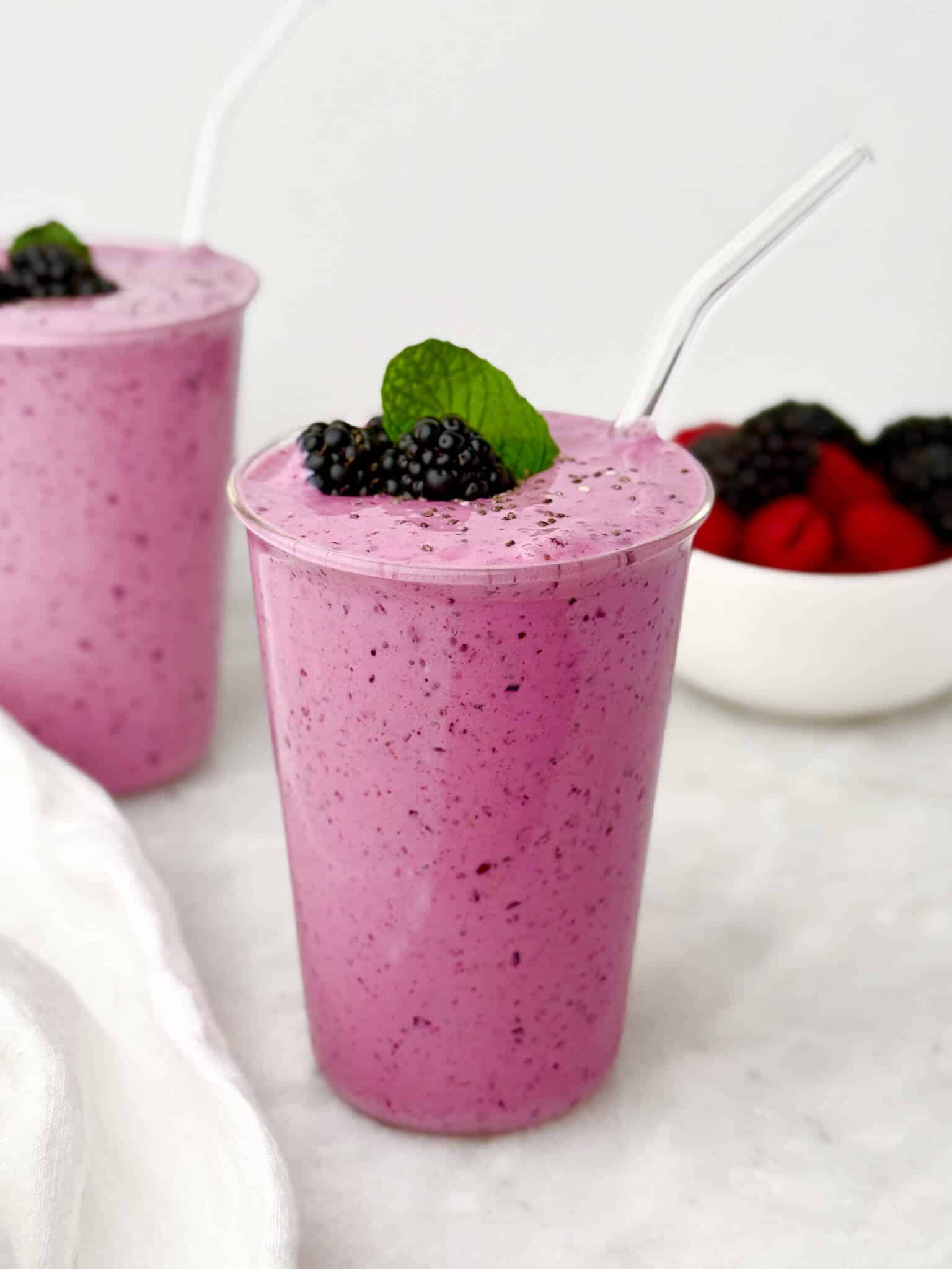 Purple berry protein smoothie in a glass with fresh blackberries and mint