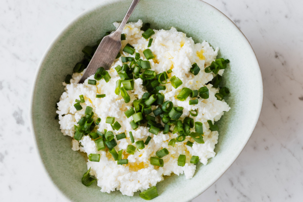 Bowl of cottage cheese garnished with fresh chives as a high protein breakfast.