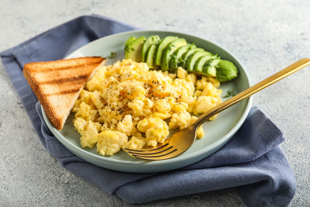 Low carb high protein scrambled eggs served with avocado slices.