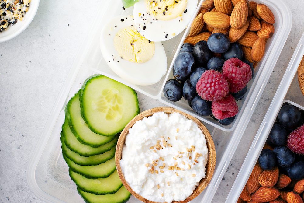 High protein low carb meal prep box with boiled eggs, cottage cheese, and fresh berries.