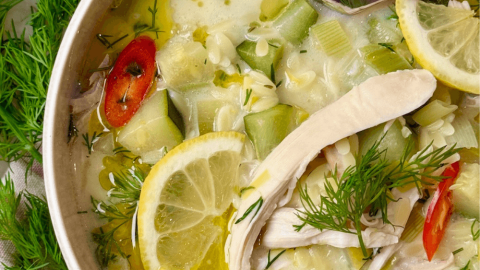 Healthy lemon chicken orzo soup with fresh dill, zucchini, and red chili in a creamy broth, served in a white bowl – healthy soup recipe.