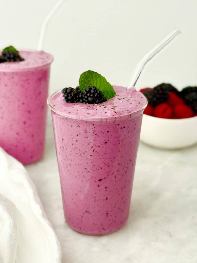 High-protein low-carb berry smoothie in a clear cup topped with fresh blackberries and mint