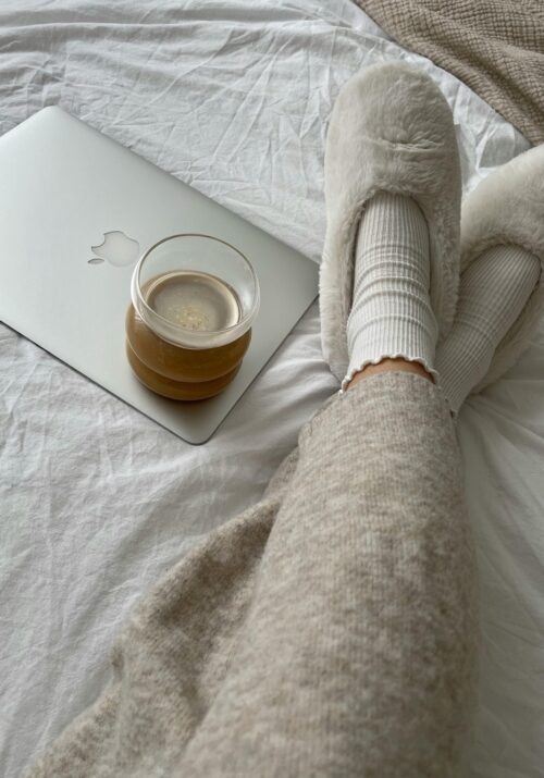 a self care sunday image of a woman's legs in cozy slippers with a cup of coffee