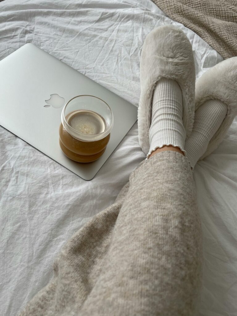 a self care sunday image of a woman's legs in cozy slippers with a cup of coffee