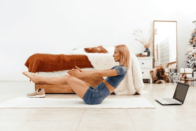 Woman practicing the hollow body hold, a deep core exercise that strengthens the pelvic floor and core.