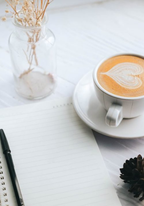 Open notebook with a pen beside a cup of coffee, perfect setup for planning goals list for 2025.