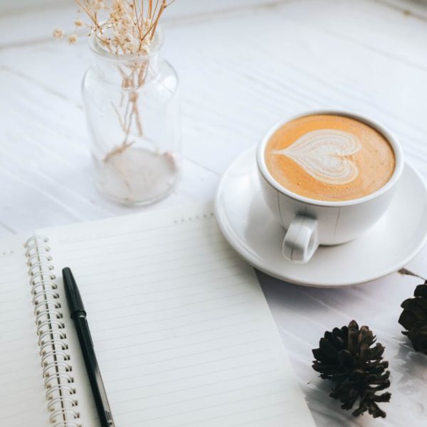 Open notebook with a pen beside a cup of coffee, perfect setup for planning goals list for 2025.