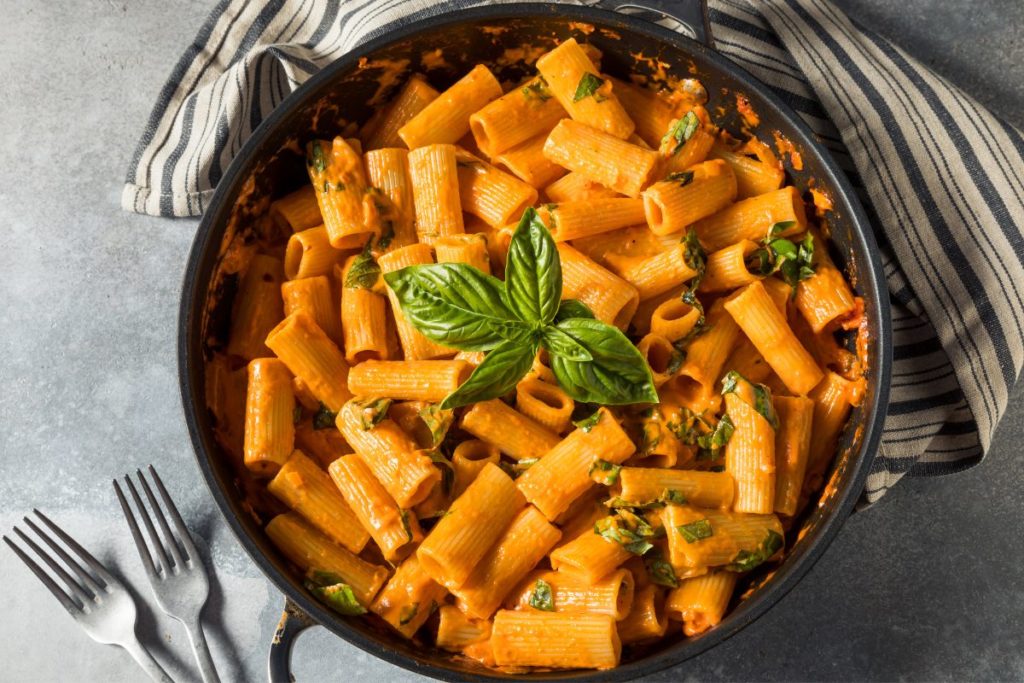 Creamy pasta in a skillet, garnished with fresh basil leaves – a delicious example of high protein vegan meal ideas.