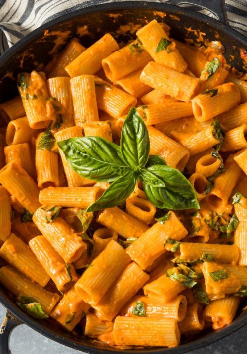 Creamy pasta in a skillet, garnished with fresh basil leaves – a delicious example of high protein vegan meal ideas.