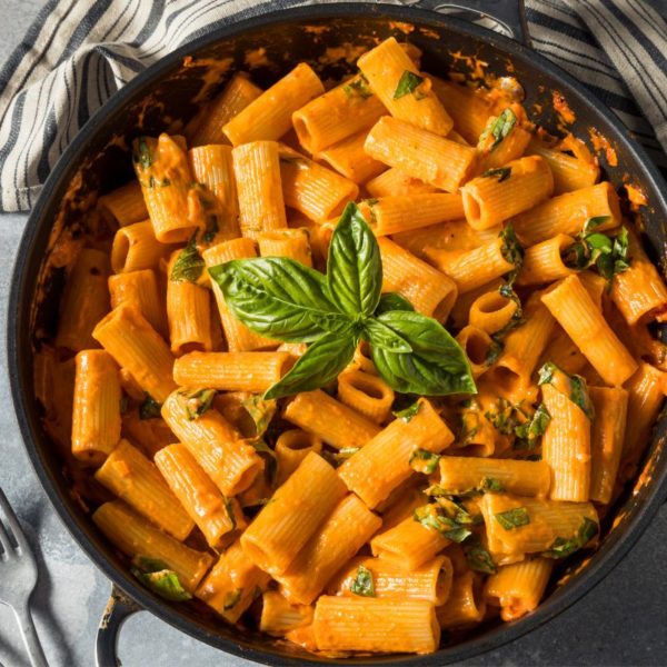 Creamy pasta in a skillet, garnished with fresh basil leaves – a delicious example of high protein vegan meal ideas.