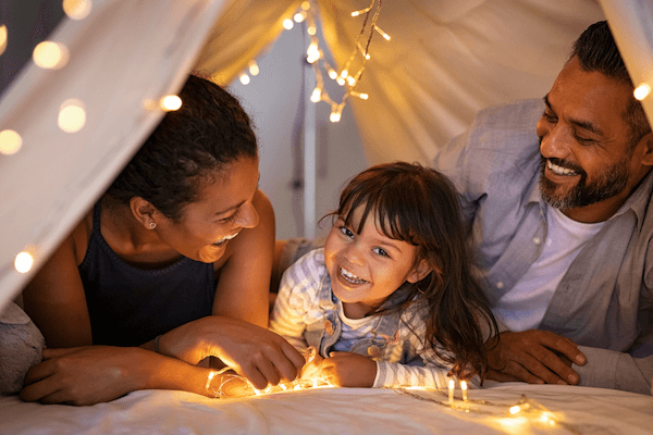 Family enjoying screen-free time in a cozy indoor blanket fort.