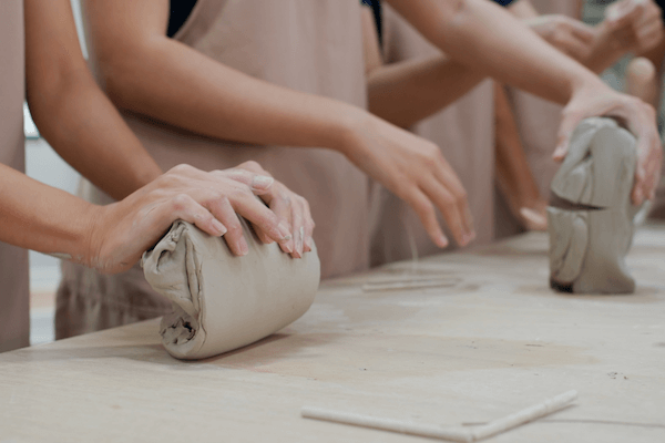 Hands working with clay in a pottery class, a creative screen-free hobby.