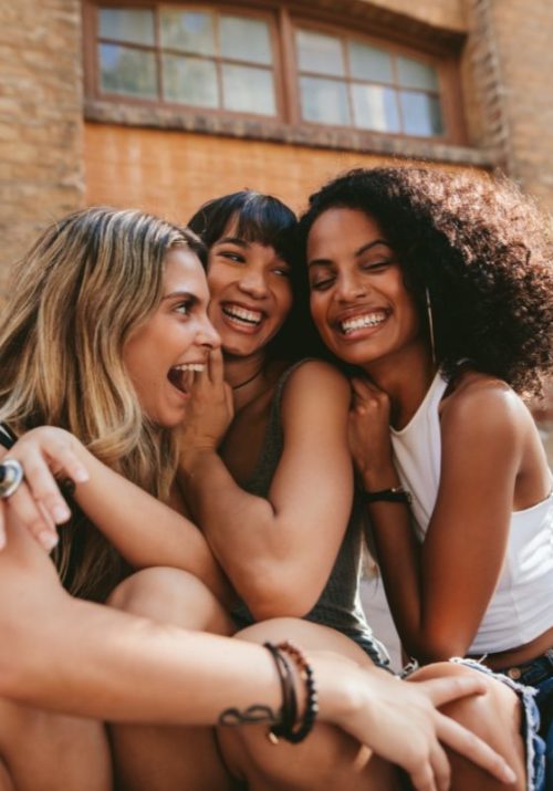 Three women making friends in a new city, sharing laughter and bonding outdoors.