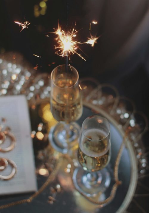 New Year resolution ideas represented through two glasses of champagne and a sparkler