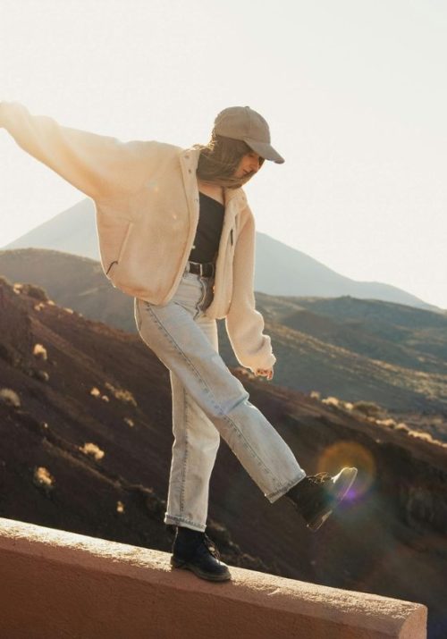 Woman balancing on a ledge in the mountains, symbolizing balance and harmony with cycle syncing workouts and diet.