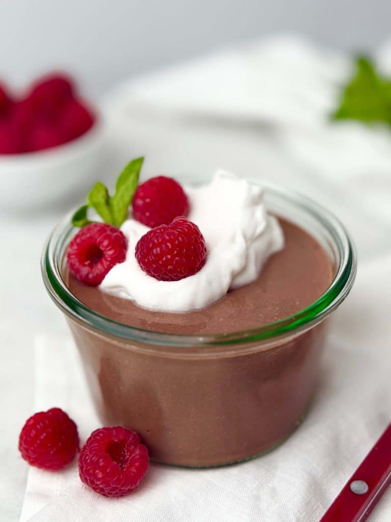 Jar of chocolate blended cottage cheese pudding topped with raspberries, a creamy high-protein breakfast prep idea with 30 grams of protein.
