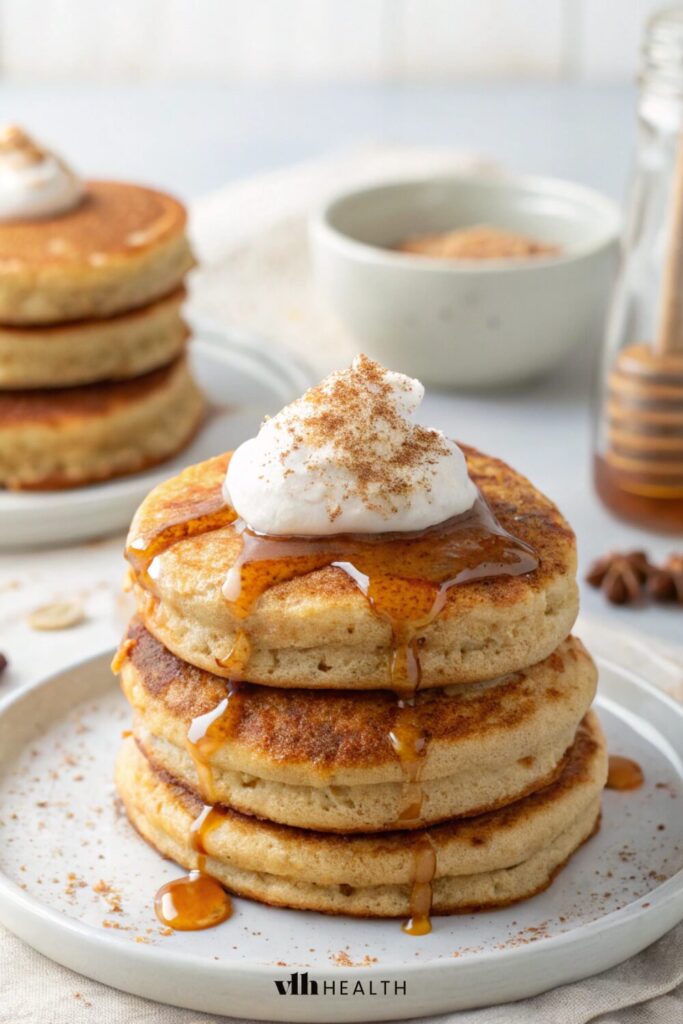 Fluffy protein pancakes stacked high, drizzled with syrup, and topped with cinnamon and Greek yogurt. A perfect high-protein low-calorie breakfast idea for meal prep and calorie deficit meals.