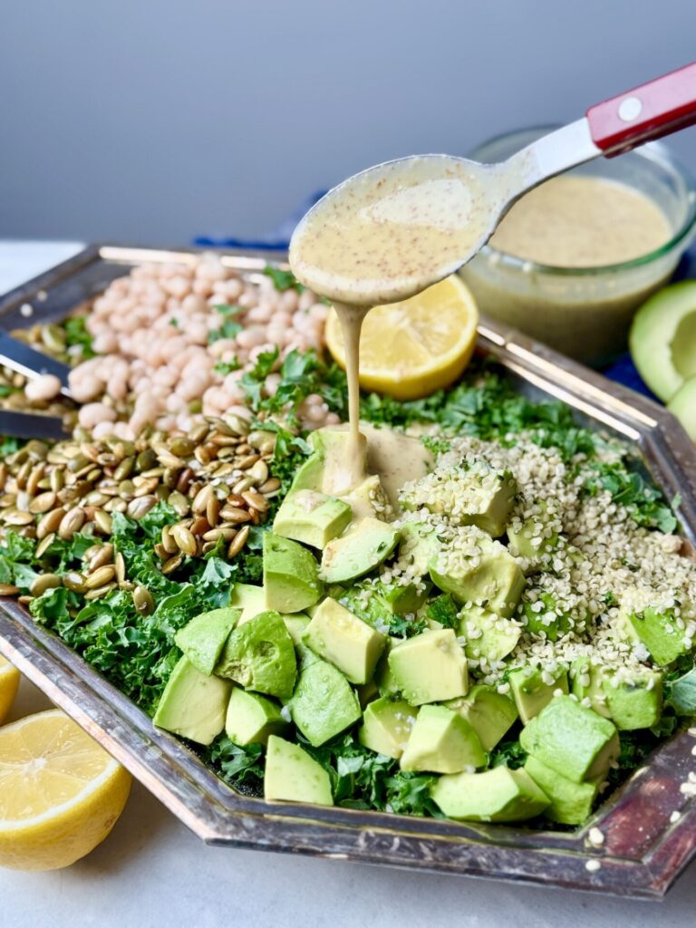 A vibrant Erewhon kale white bean salad drizzled with a creamy mustard dressing. This kale and bean salad recipe is packed with protein from white beans, hemp seeds, and pumpkin seeds, topped with avocado for a delicious and nutritious meal.