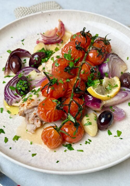 mediterranean chicken sheet pan dinner with chicken thighs, tomatoes, and olives.