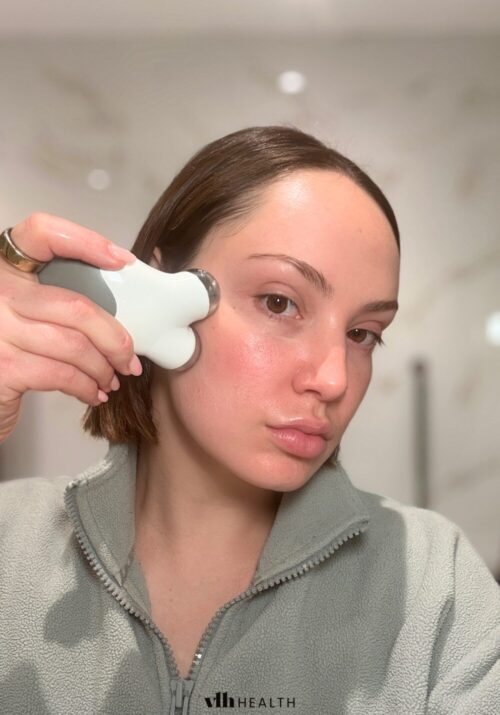 Woman using a microcurrent device on her cheek to lift and tone facial muscles.