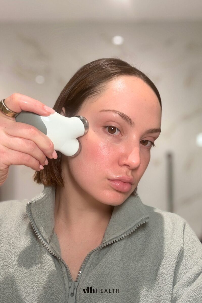 Woman using a microcurrent device on her cheek to lift and tone facial muscles.