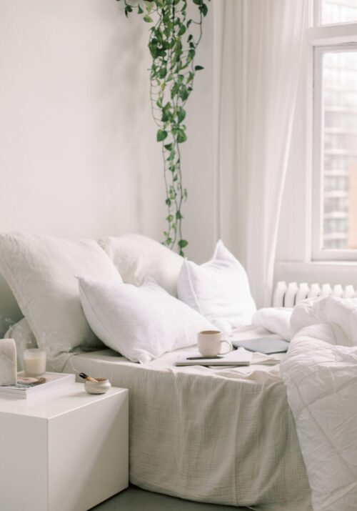 Cozy minimalist bedroom with a notebook, pen, and coffee cup on a bed—an ideal setup for practicing morning journaling and discovering what are morning pages.