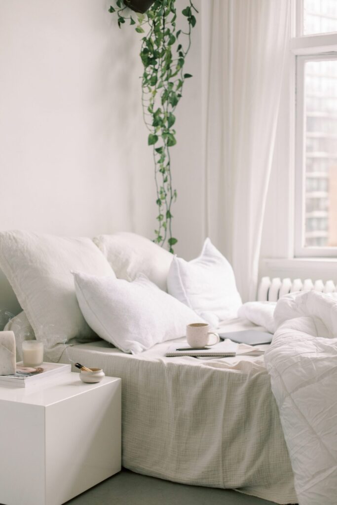 Cozy minimalist bedroom with a notebook, pen, and coffee cup on a bed—an ideal setup for practicing morning journaling and discovering what are morning pages.