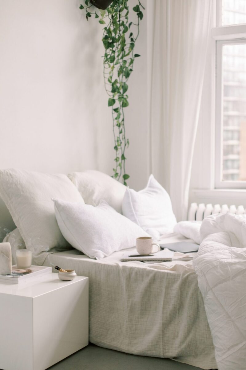 Cozy minimalist bedroom with a notebook, pen, and coffee cup on a bed—an ideal setup for practicing morning journaling and discovering what are morning pages.