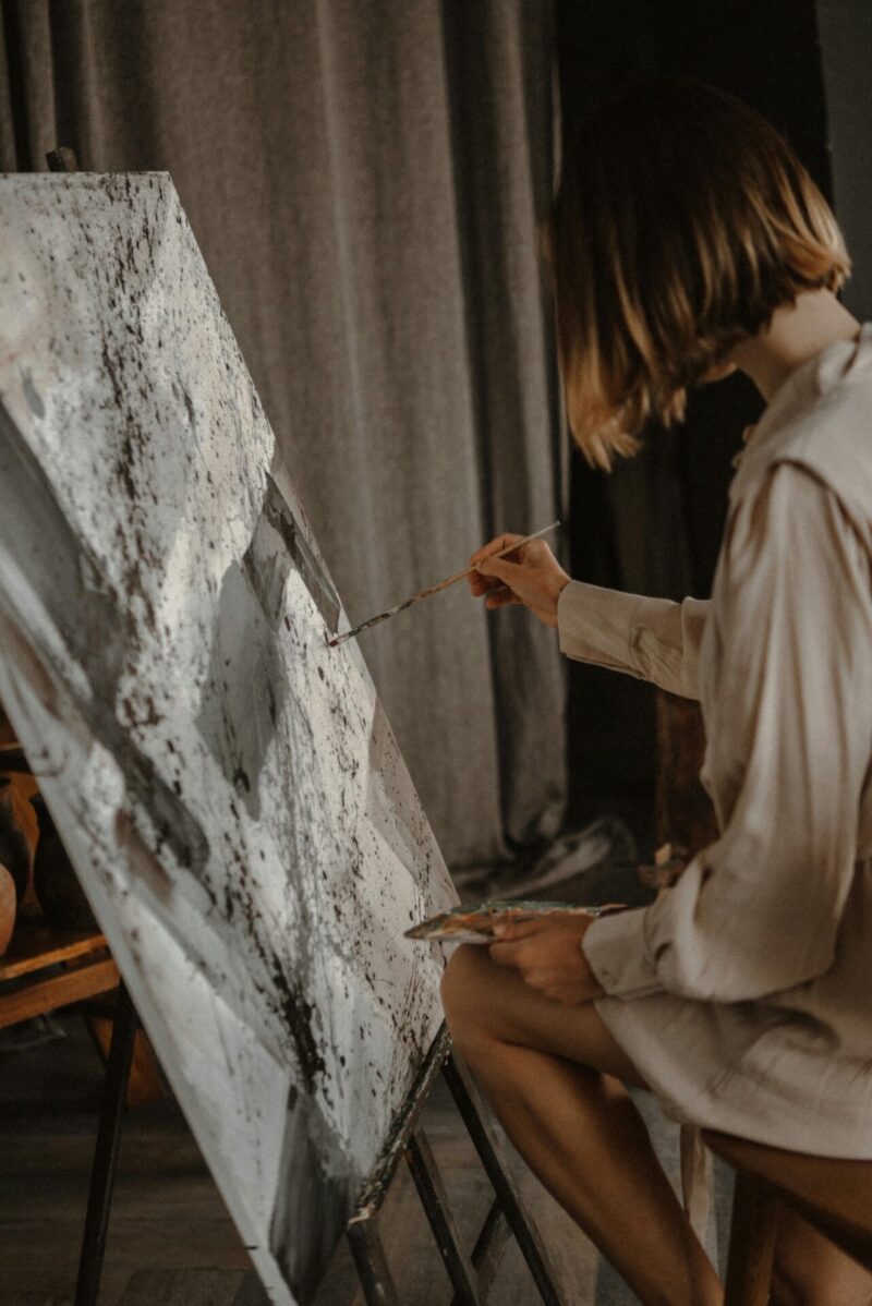 a woman enjoying one of her adhd hobbies painting an abstract piece of art