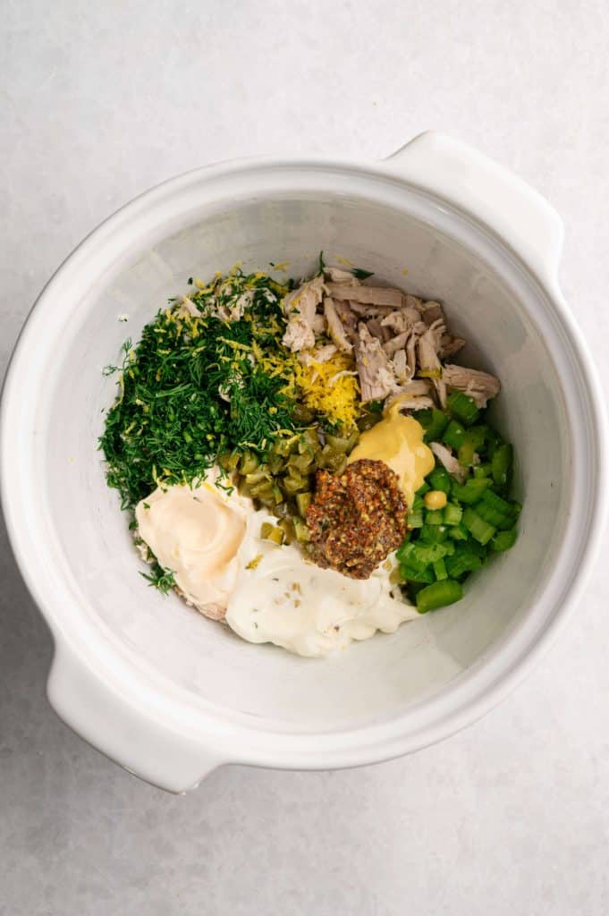 Ingredients for high protein dill pickle chicken salad including shredded chicken, Greek yogurt, mayo, Dijon mustard, dill pickles, celery, lemon zest, and fresh dill.