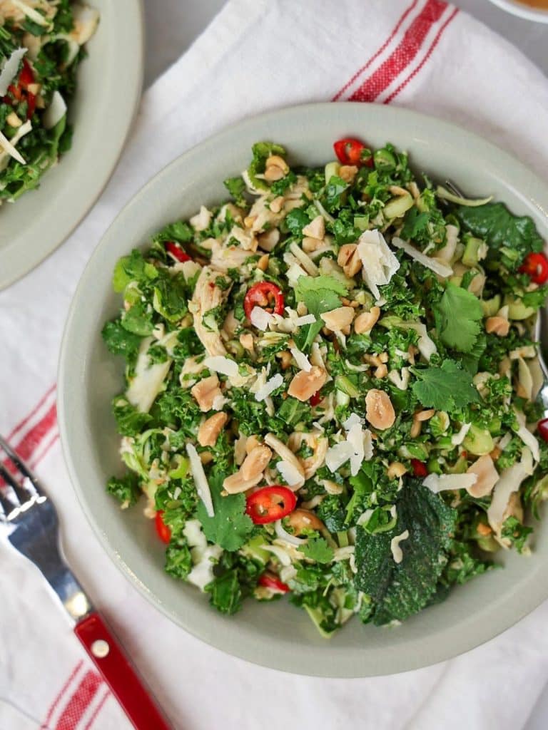 Emerald kale salad served in bowls with peanut vinaigrette, chili, and fresh herbs
