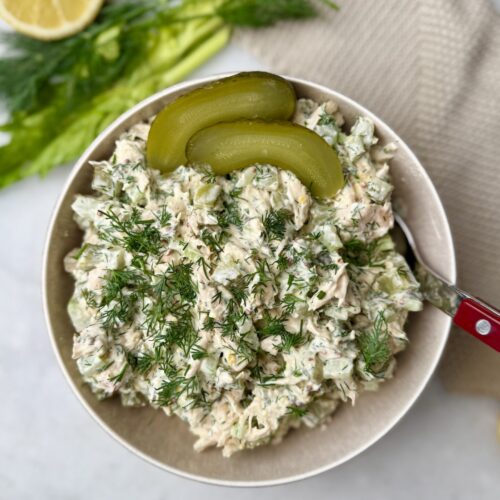 Top-down view of dill pickle chicken salad garnished with fresh dill and pickle slices.