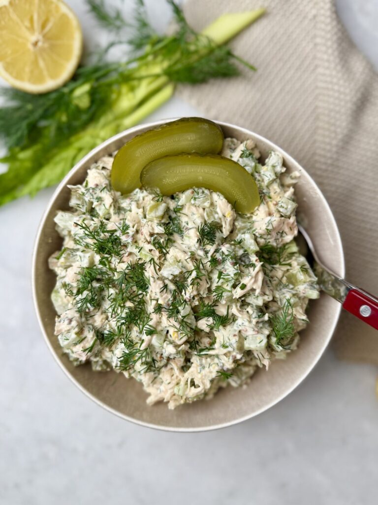 Top-down view of dill pickle chicken salad garnished with fresh dill and pickle slices.