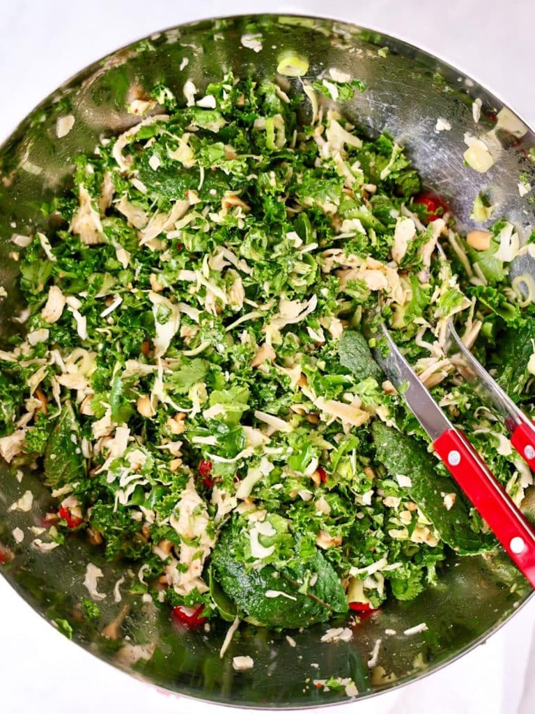 Tossing Houston's kale salad with peanut dressing in a large mixing bowlTossing Houston's kale salad with peanut dressing in a large mixing bowl