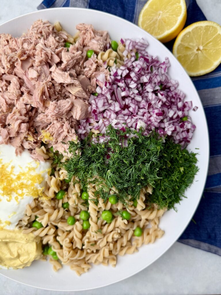 Ingredients for high-protein tuna pasta salad, including tuna, red onion, fresh dill, Greek yogurt, and whole wheat pasta.