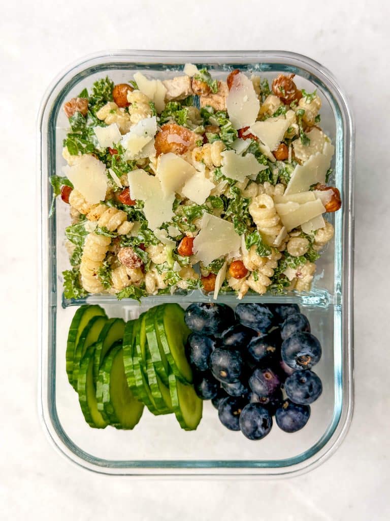 Chicken caesar pasta salad meal prep container with cucumber slices and blueberries
