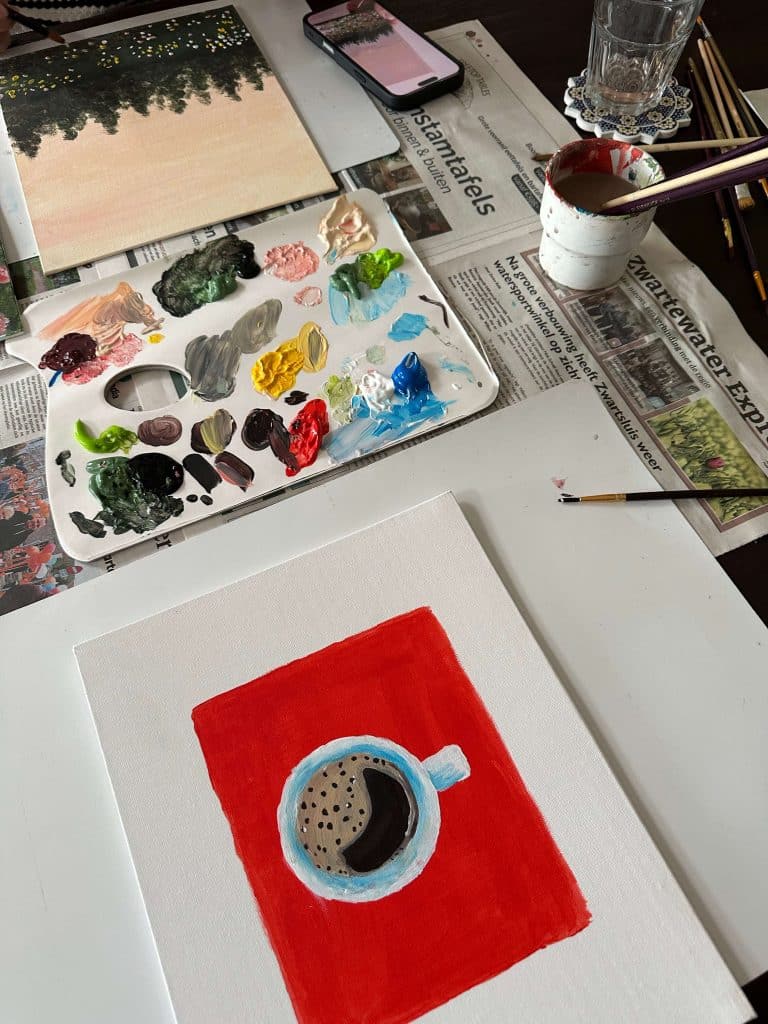 a painting workspace with brushes, paint, and a canvas of a coffee cup, symbolizing creative and relaxing hobbies