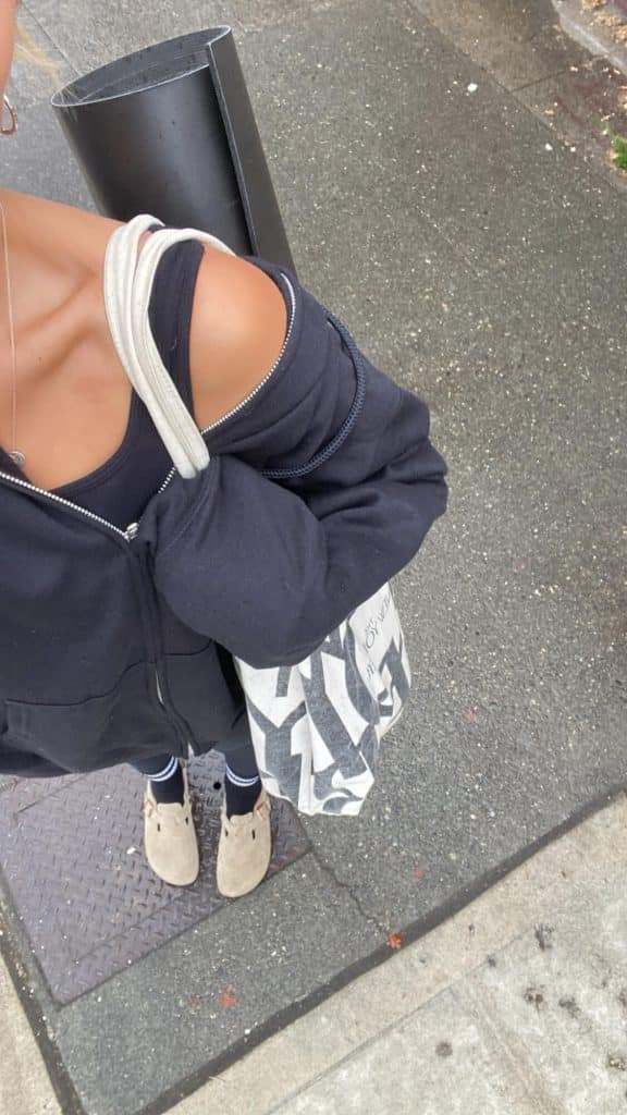 a woman walking outside with a coffee and yoga mat, illustrating healthy daily habits for a balanced life