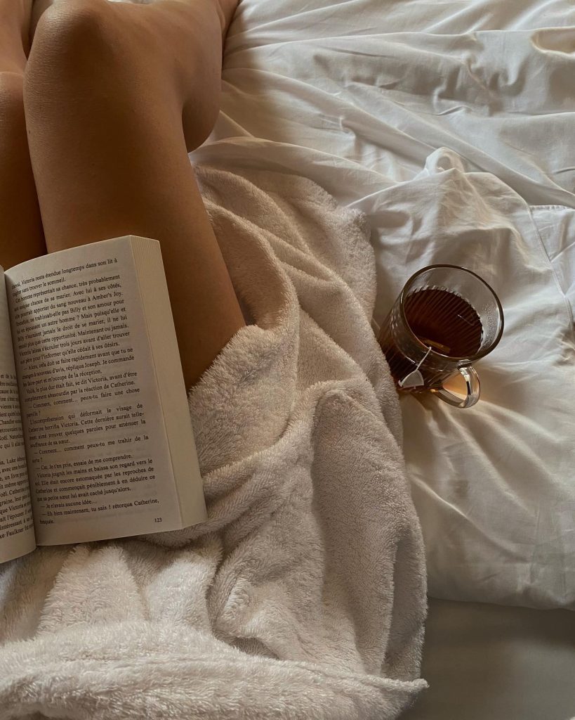 a woman reading in bed as part of her daily self care checklist.